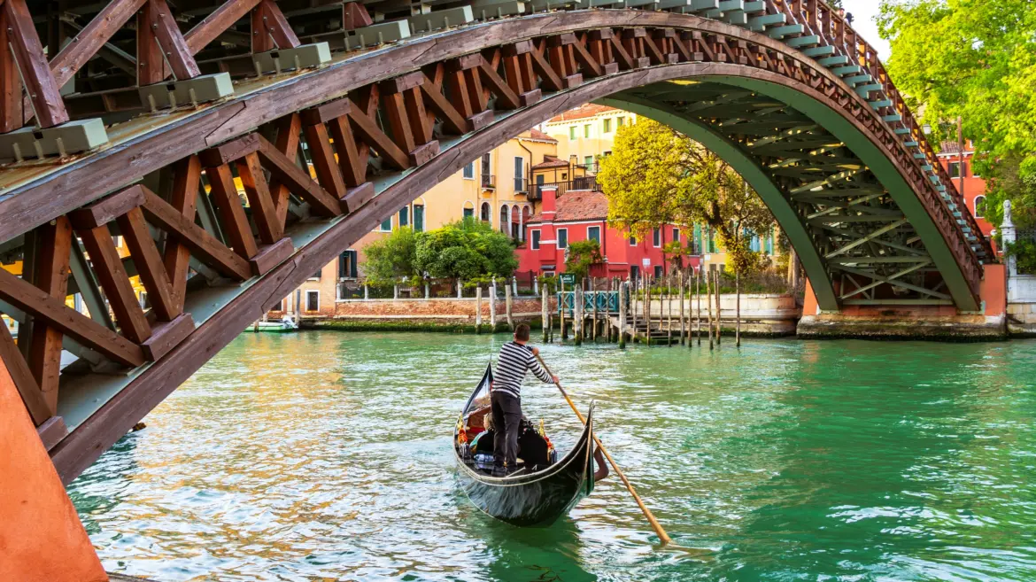 Gondola gliding beneath Ponte dell'Accademia Accademia Bridge passing quietly along Grand Canal Venice Italy