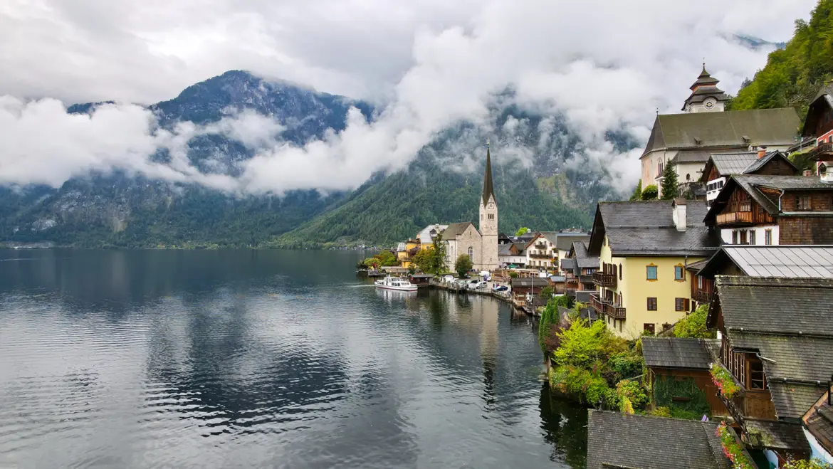 Misty view village Hallstatt Austria church historic town center framed clouds alpine scenery captured cloudy day quiet beauty timeless character dramatic natural setting serene contrast Vienna urban elegance