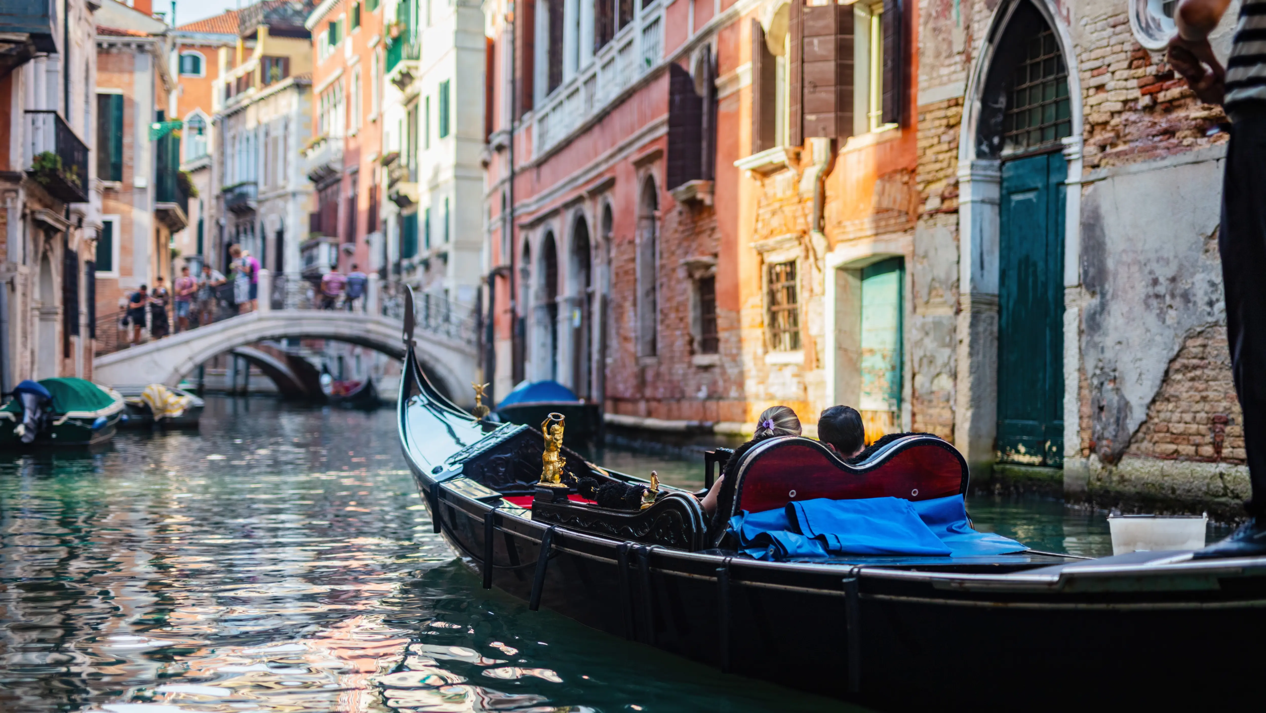 Iconic black gondola drifting across quiet Venetian canal historic buildings Venice Italy