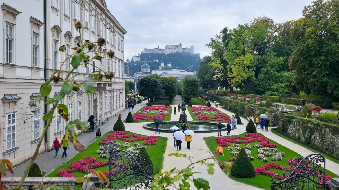 View from Mirabell Gardens Salzburg Austria looking toward Hohensalzburg Fortress overlooking historic city formal Baroque gardens frame fortress harmonious blend landscaped elegance alpine surroundings architectural history