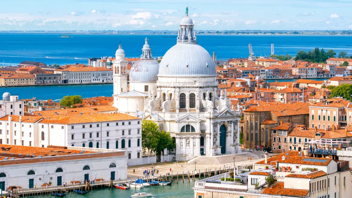 Aerial view Santa Maria della Salute white Baroque domes overlooking Grand Canal Venetian Lagoon with terracotta rooftops Venice Italy