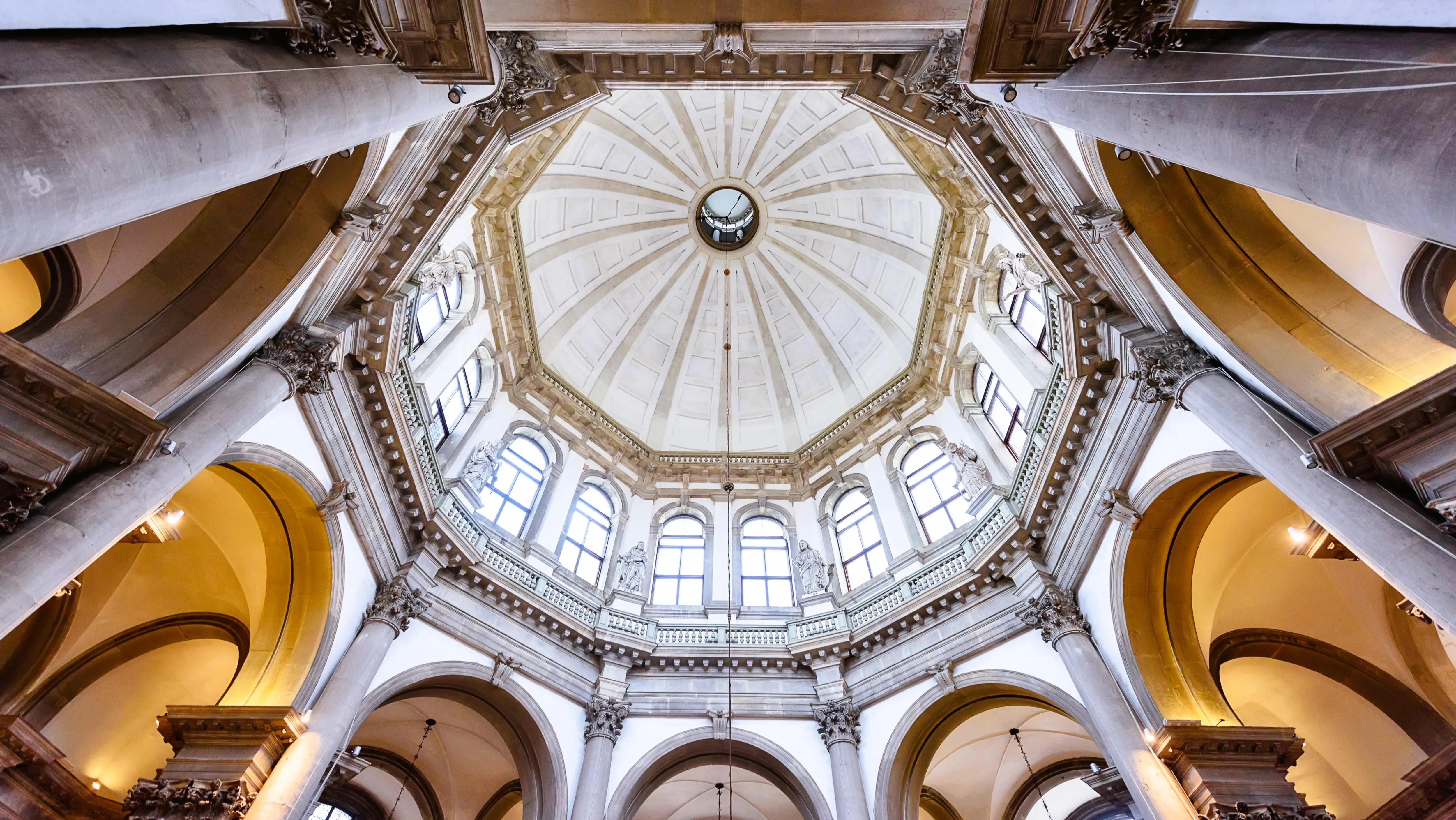 Looking up at massive Baroque dome Santa Maria della Salute church with natural light entering through multiple arched windows Venice