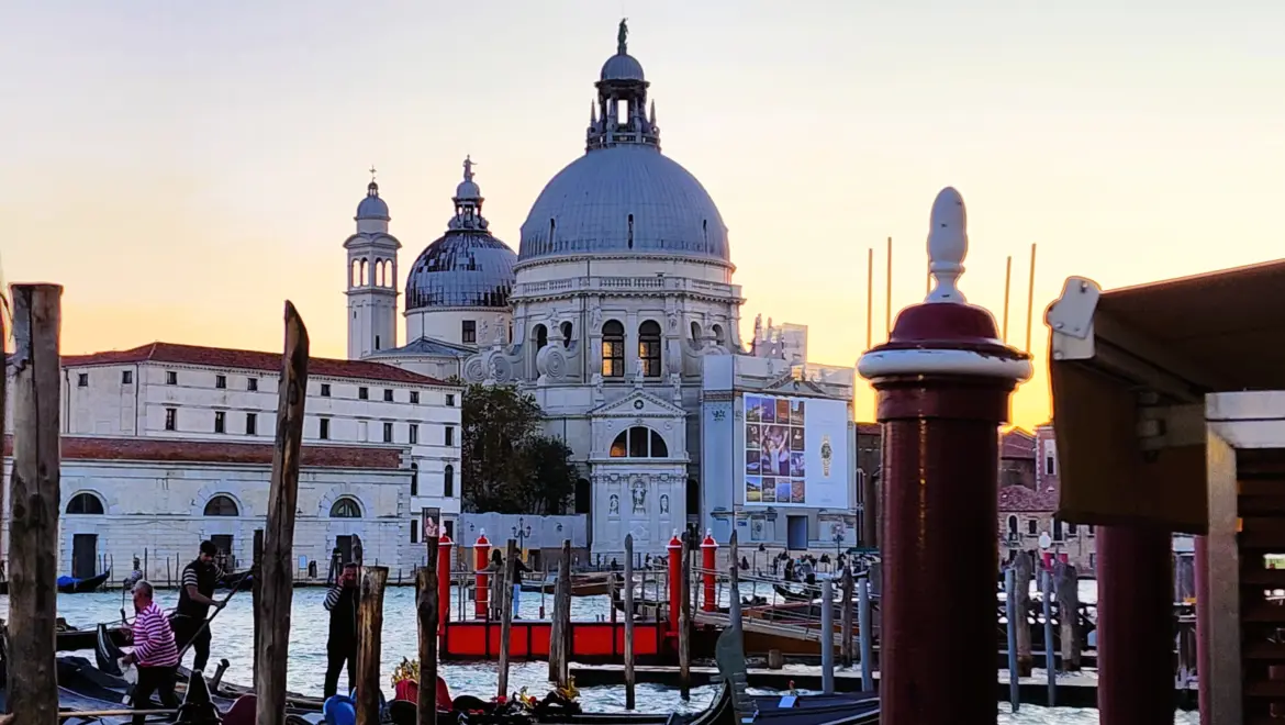 Santa Maria della Salute church at sunset with gondolier and traditional mooring posts Grand Canal Venice October 2024