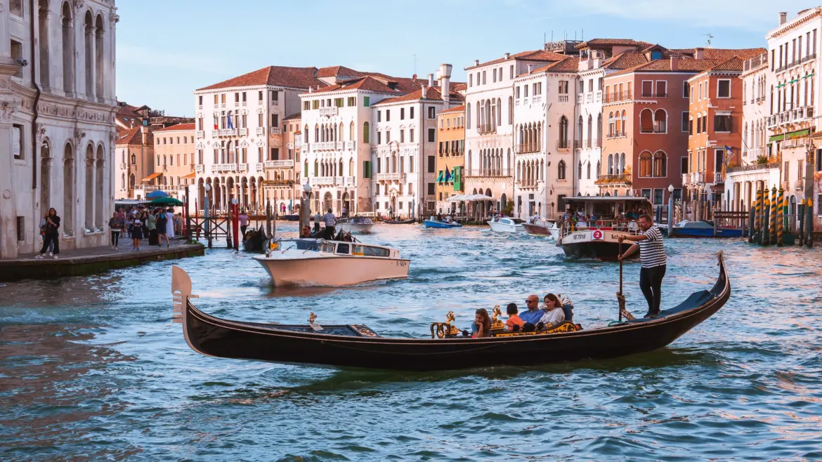 Traditional black gondolas gliding along Grand Canal with historic buildings Venice Italy
