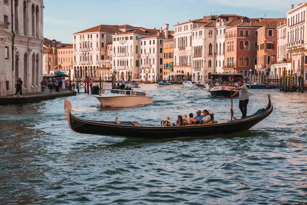 Traditional black gondolas gliding along Grand Canal with historic buildings Venice Italy