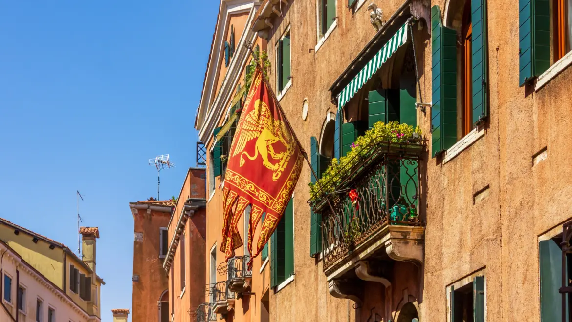 Traditional Venetian architecture featuring red and gold flag winged Lion of Saint Mark historic symbol Venice balcony