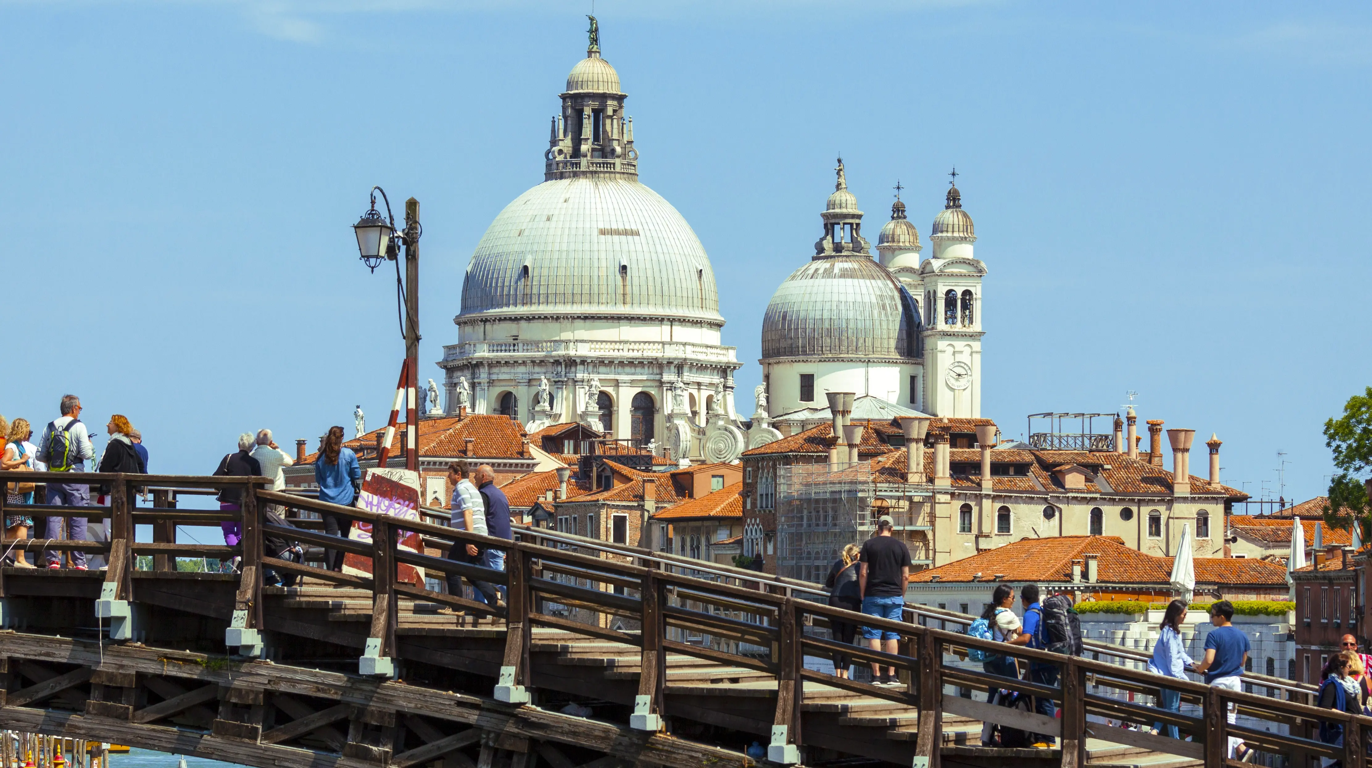 Travelers pausing on Ponte dell'Accademia Accademia Bridge afternoon admiring Santa Maria della Salute church Venice Italy