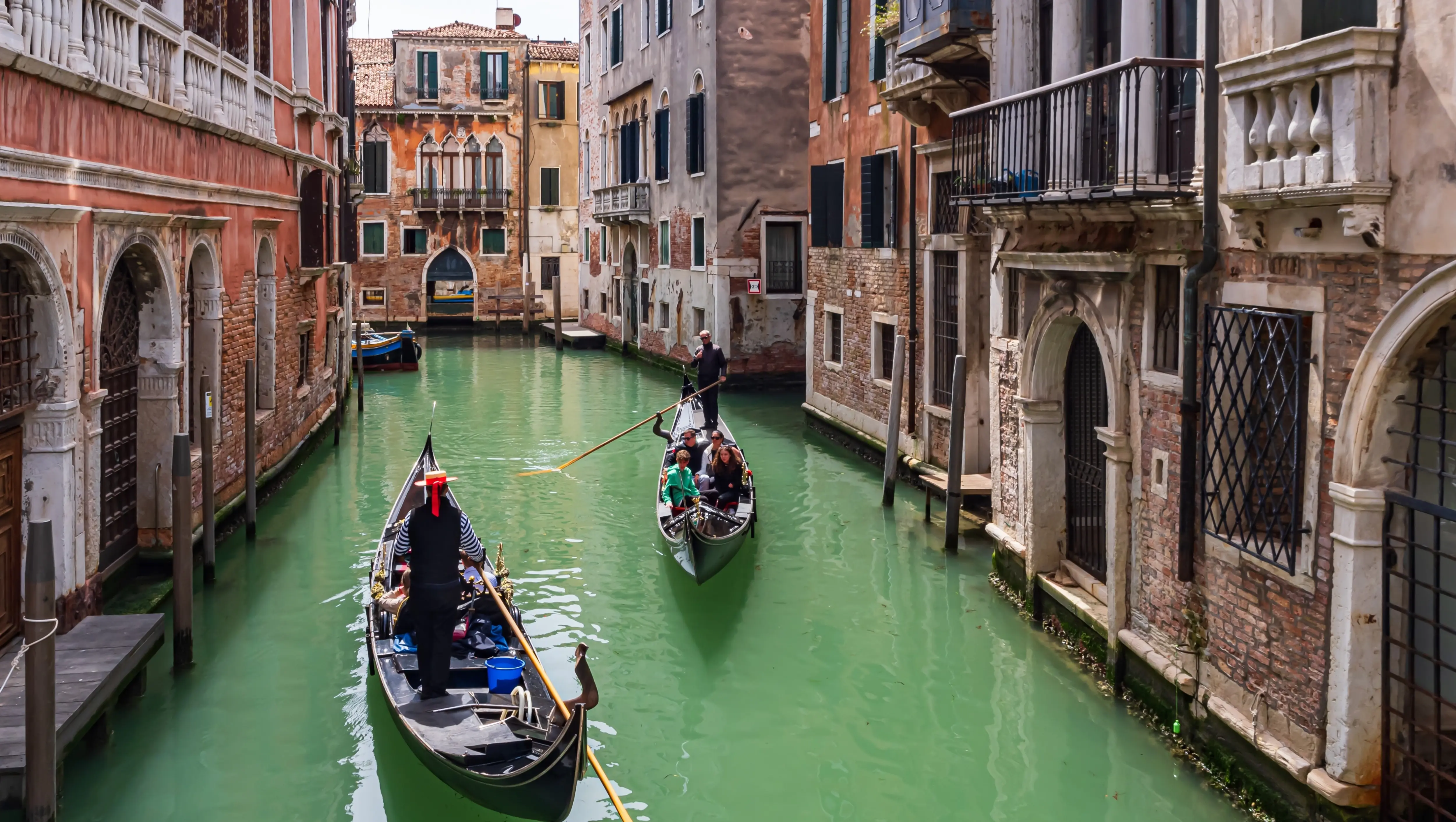 Venetian gondolas gliding through quiet residential waterways back canals Venice Italy