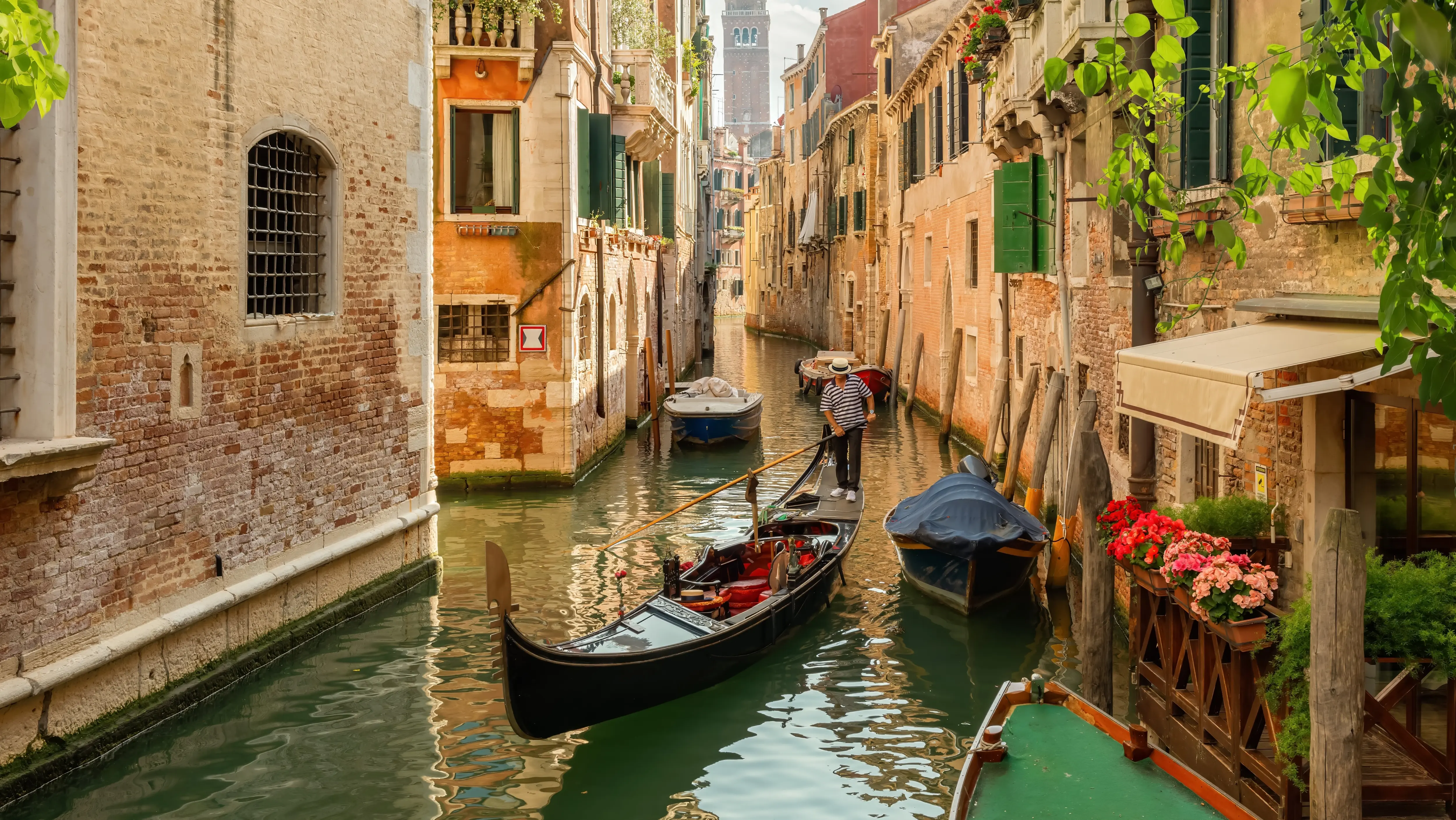 Traditional Venetian gondolier gondolieri navigating gondola through narrow side canal Venice Italy