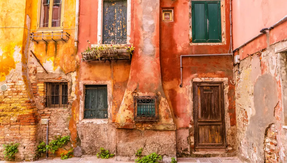 Worn yet colorful historic building Castello district Venice Italy time-softened façades faded tones quiet charm lived-in neighborhood away tourist routes