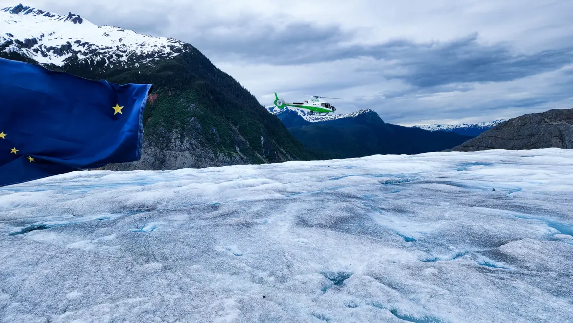 The Alaska state flag displayed on the surface of the Mendenhall Glacier during a TEMSCO tour in Juneau