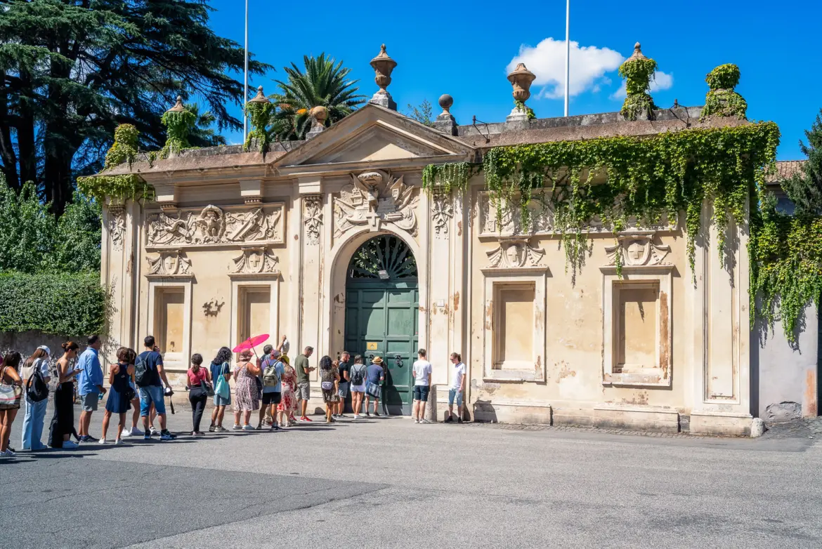 Visitors queuing at the famous Aventine Keyhole door of the Knights of Malta on Aventine Hill in Rome with ornate gate and ivy-covered wall