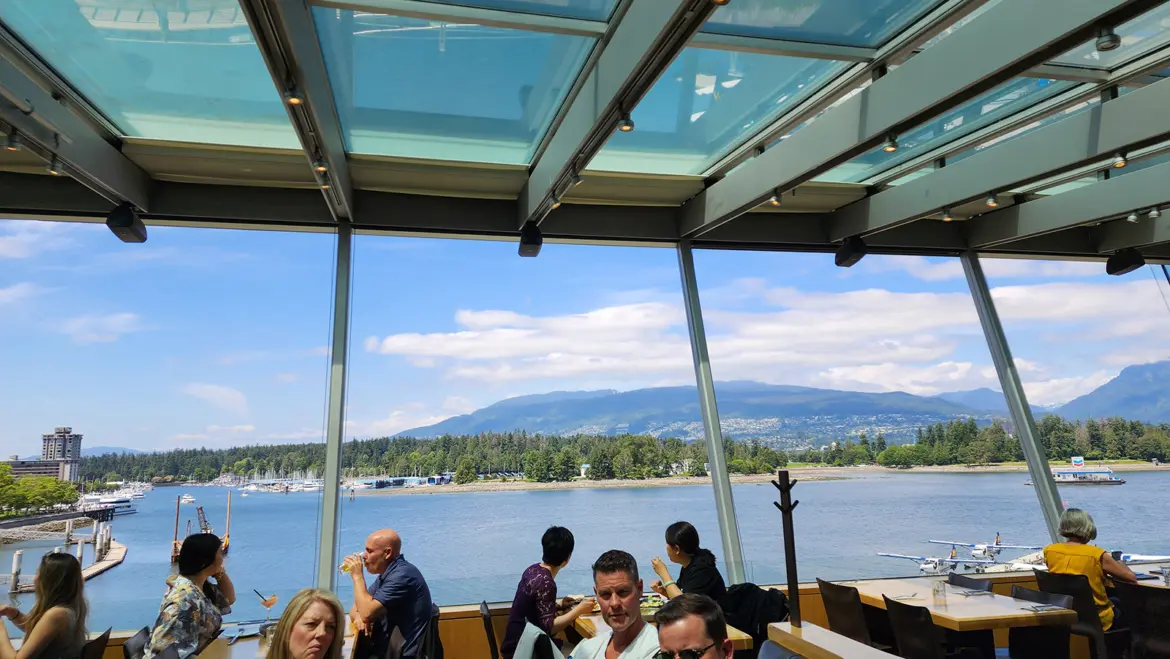 Cactus Club Cafe Coal Harbour Patio Diners Seaplane Mountains Vancouver Diners on the patio at Cactus Club Cafe Coal Harbour with views of Stanley Park, the North Shore mountains, and a seaplane docked at the harbour