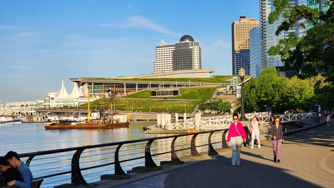 People walking the Coal Harbour seawall in Vancouver with the Convention Centre green roof visible