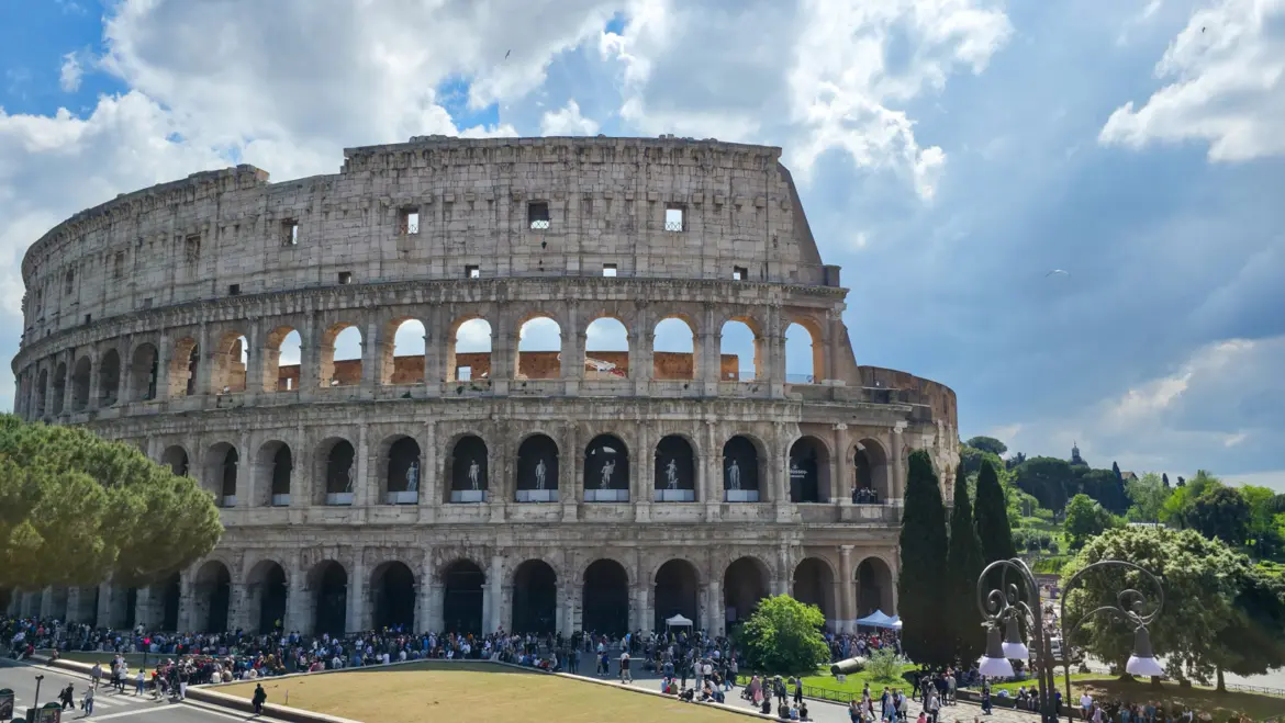 The Colosseum in Rome Italy viewed from outside showing the full scale of the ancient amphitheater under a dramatic cloudy sky