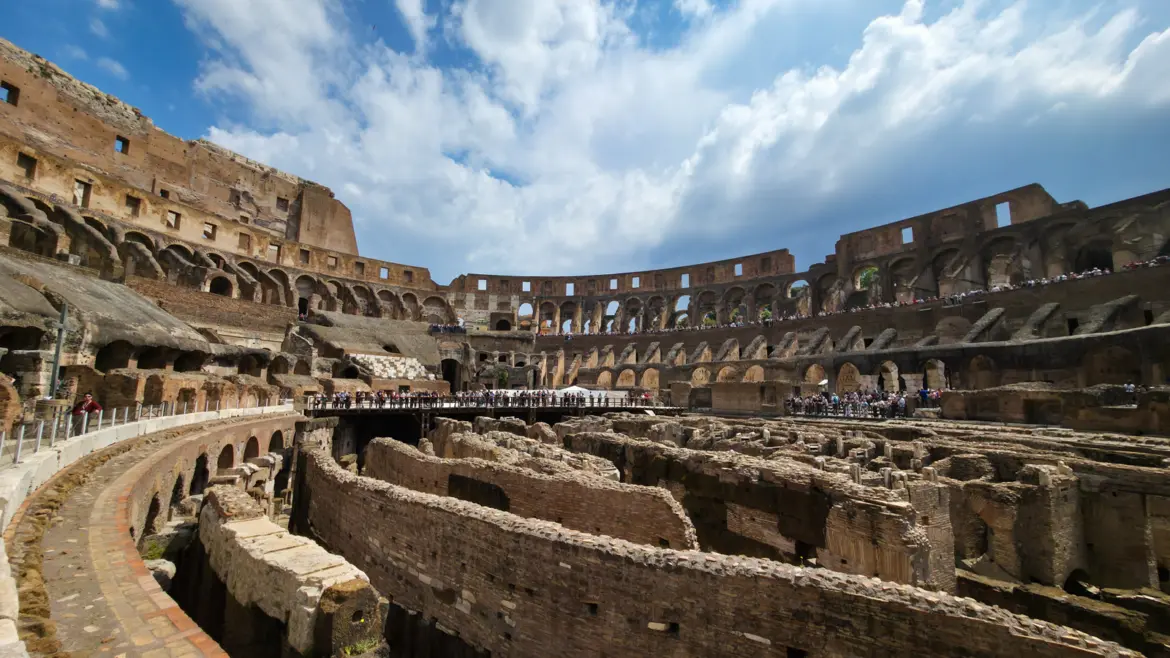 Interior view of the Colosseum in Rome Italy showing the arena floor underground chambers and tiered seating under dramatic clouds