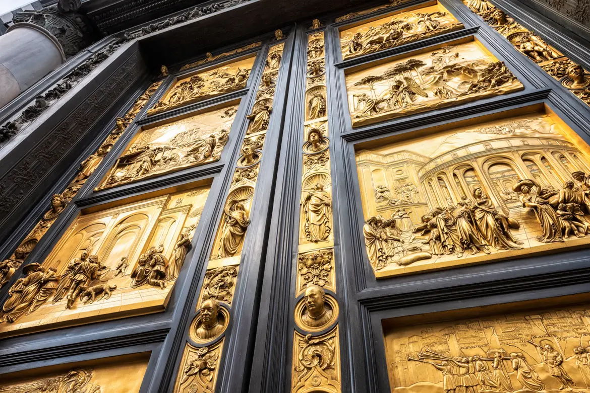 Detail of Lorenzo Ghiberti’s Gates of Paradise at the Florence Baptistery highlighting intricate gilded bronze panels depicting Old Testament scenes that helped define early Renaissance sculpture and perspective