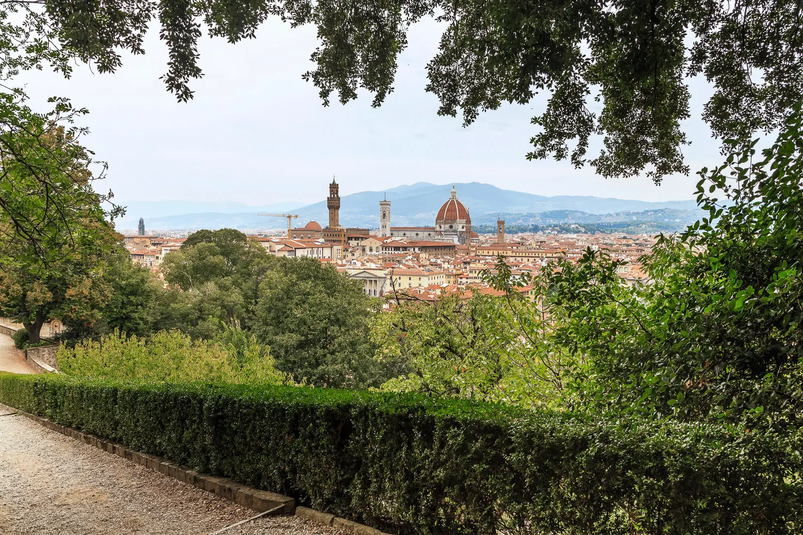 Panoramic view of Florence from Giardino Bardini showing the Duomo dome and Giotto Bell Tower rising above rooftops framed by garden trees