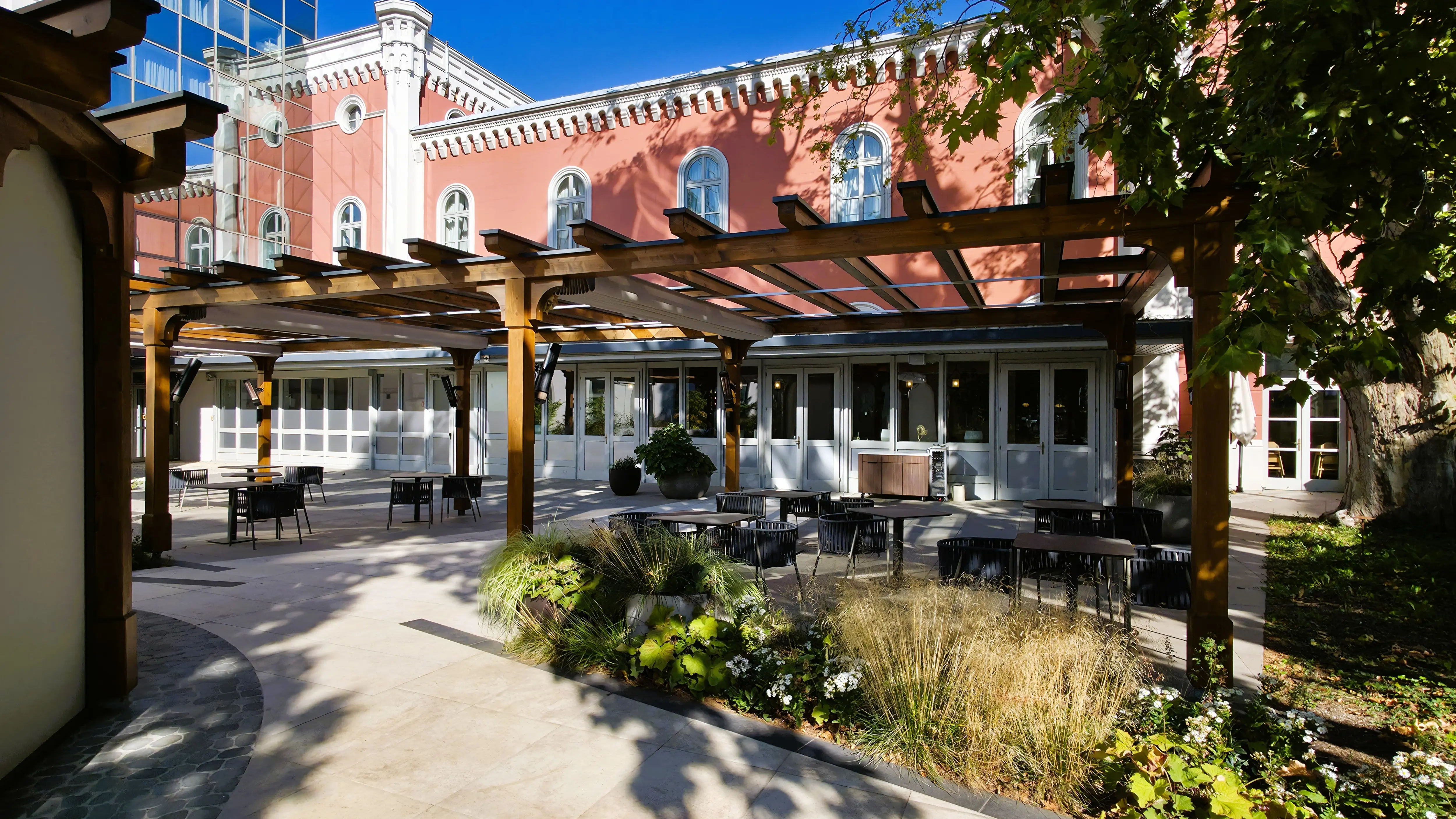 The outdoor terrace at the Imperial Riding School, Autograph Collection, overlooking the hotel’s private garden in autumn
