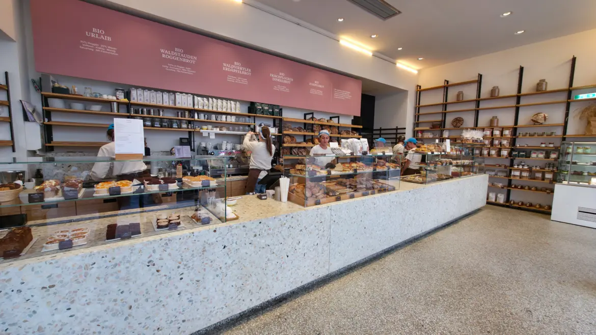 The warm, modern interior of Joseph Brot in Vienna featuring wood tones and open bread displays