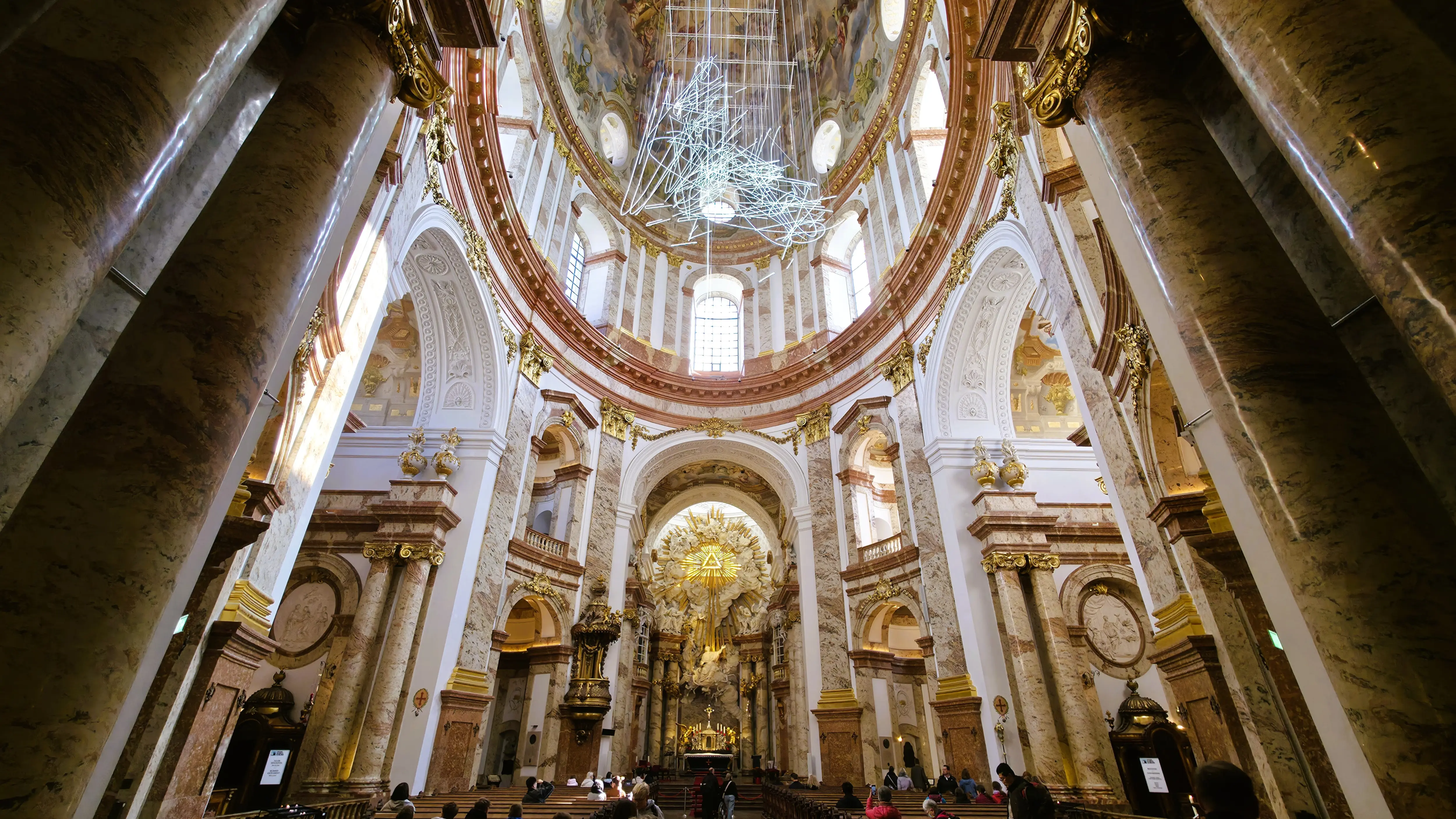 The interior and high altar of the Karlskirche in Vienna, Austria, with light filling the Baroque space beneath the frescoed dome