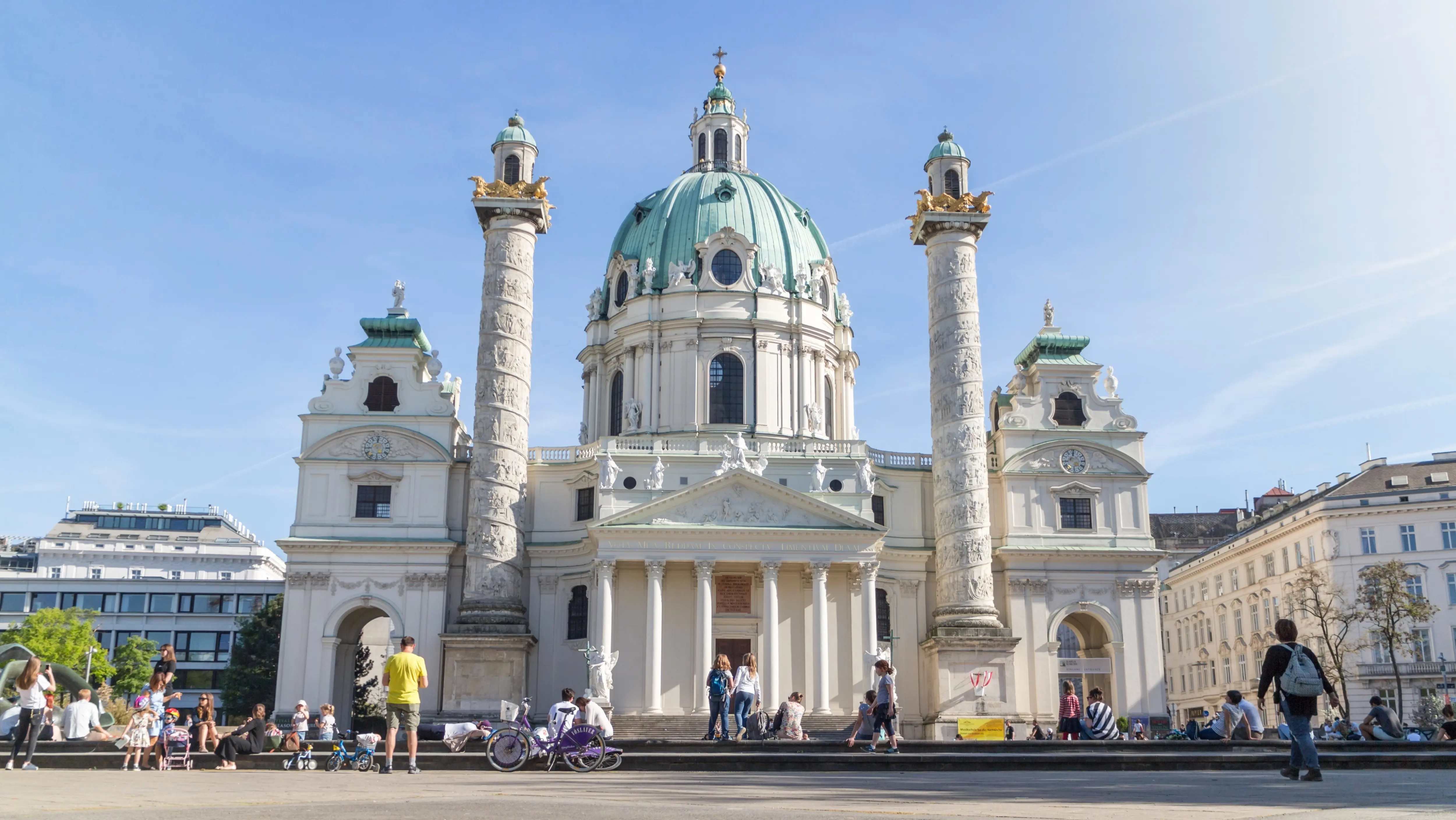 People gathering in front of Karlskirche at Karlsplatz in Vienna, where the church feels like a calm presence within everyday city life