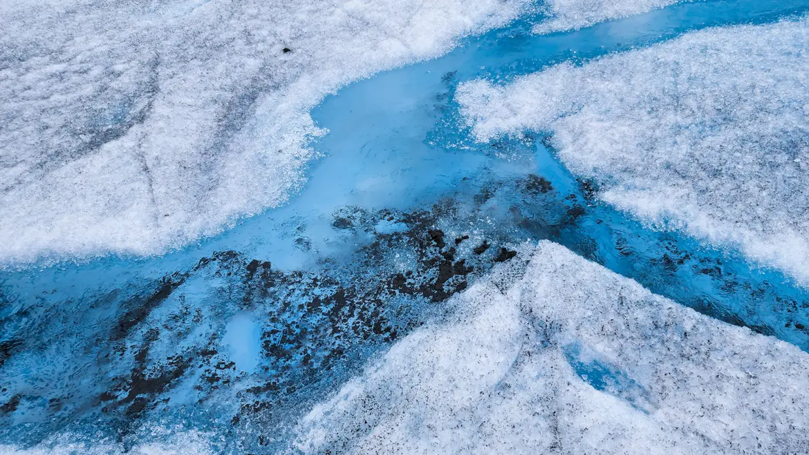 Blue meltwater stream flowing across the surface of the Mendenhall Glacier in Juneau, Alaska