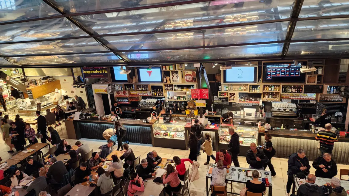 Food stalls and diners inside Mercato Centrale in Florence enjoying Tuscan specialties