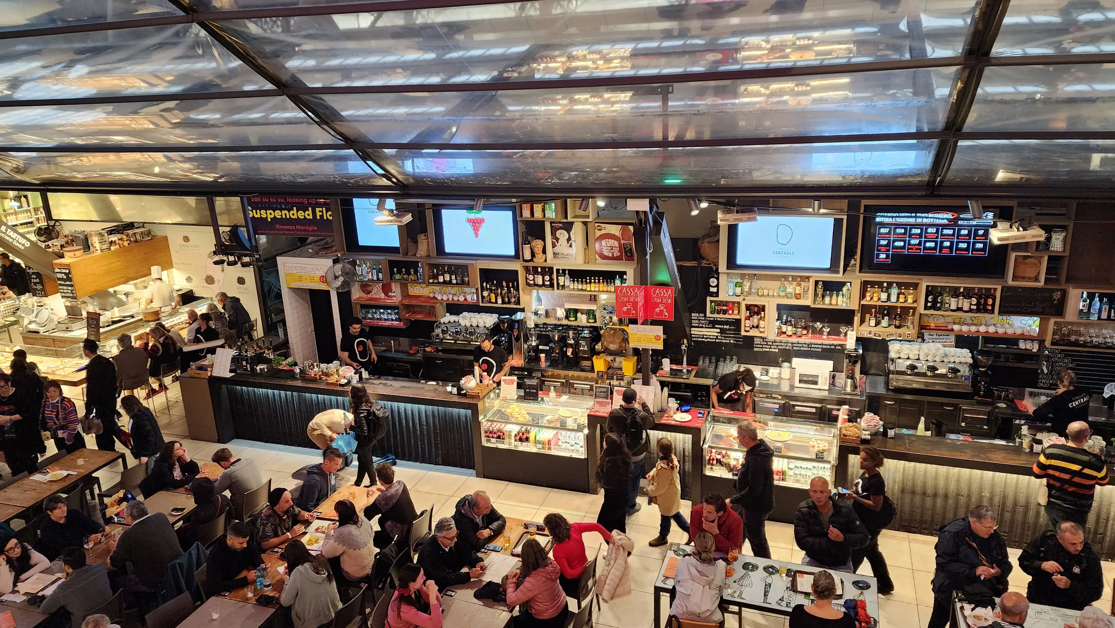 Food stalls and diners inside Mercato Centrale in Florence enjoying Tuscan specialties