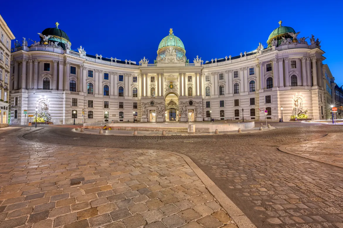 Michaelerplatz in Vienna at night, facing the illuminated Michaelertrakt (St. Michael’s Wing) of the Hofburg Palace