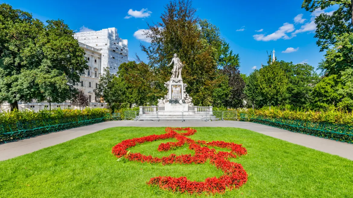 The Mozart statue in Burggarten, Vienna, surrounded by manicured gardens and greenery near the Hofburg Palace