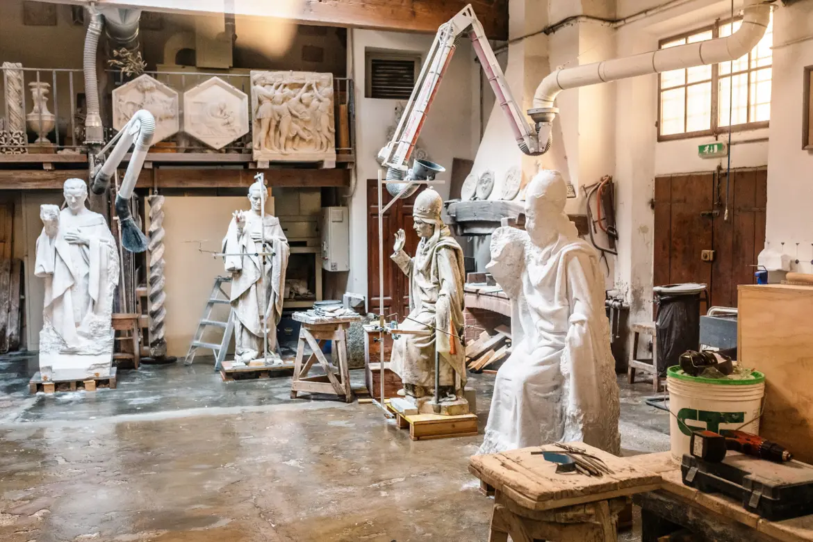 Traditional Florentine artisan workshop in Oltrarno restoring medieval religious statues with plaster figures and tools