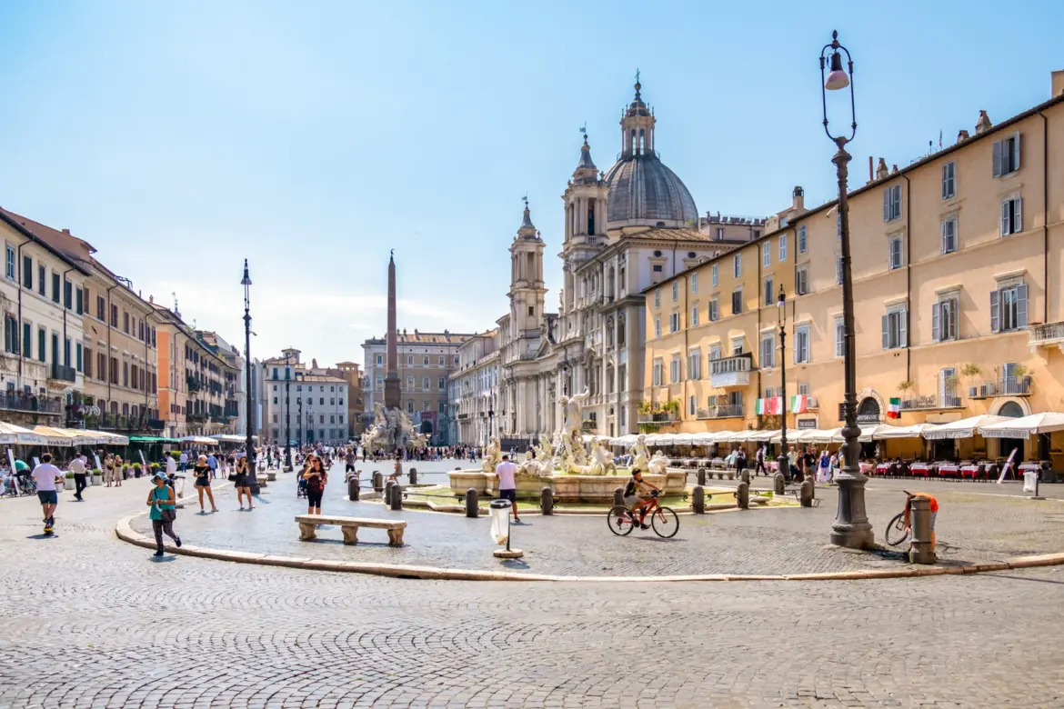 Piazza Navona in Rome Italy with Bernini’s Fountain of the Four Rivers cafes and Baroque architecture under clear blue sky