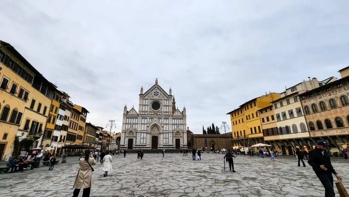 Visitors in Piazza Santa Croce in Florence with the basilica Neo-Gothic facade in the background under overcast sky