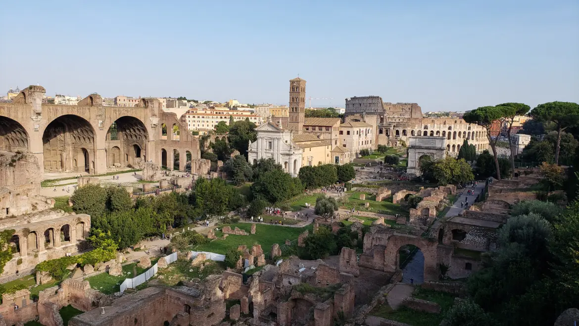 The Roman Forum ruins in Rome with ancient temple columns arches and pathways stretching into the distance