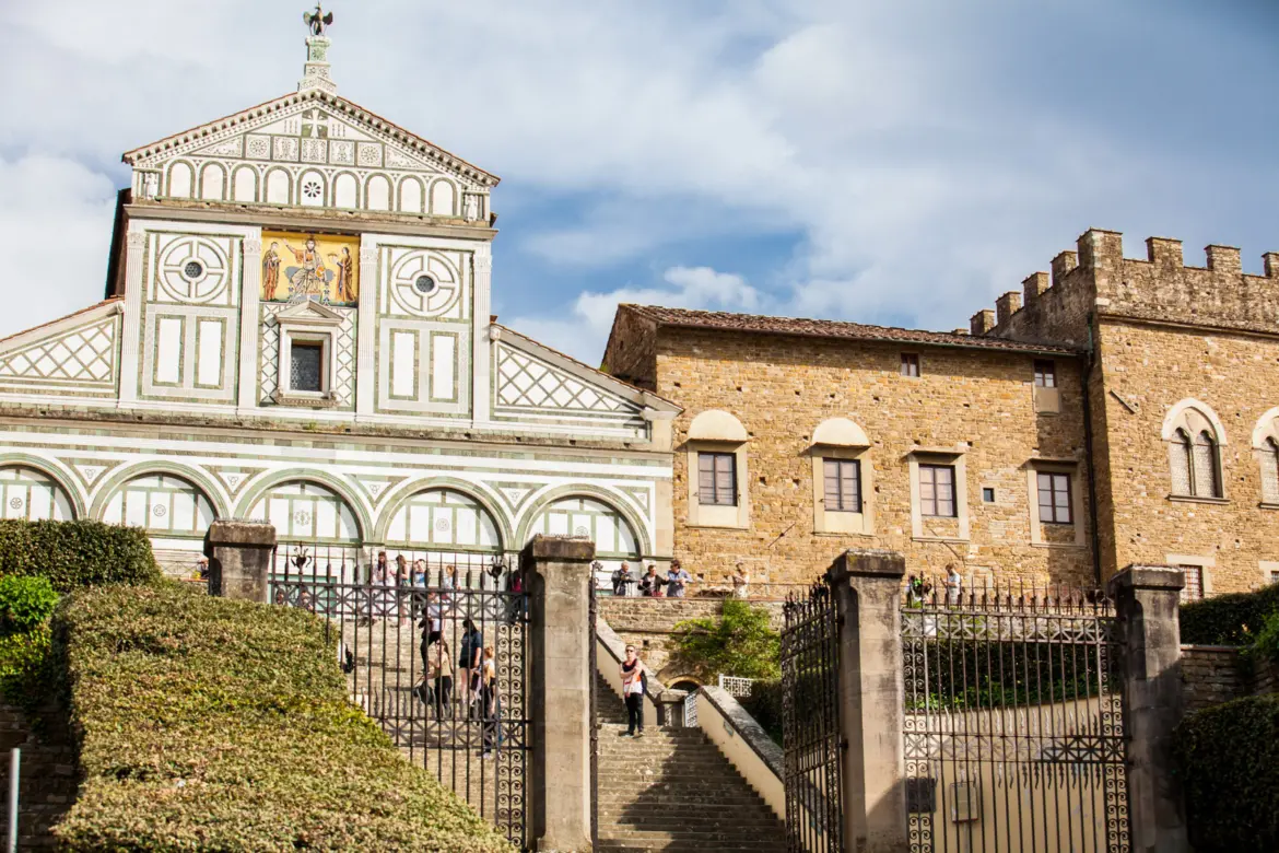 San Miniato al Monte basilica rising above Florence on Monte alle Croci, showing the Romanesque church exterior and fortified walls in warm afternoon light