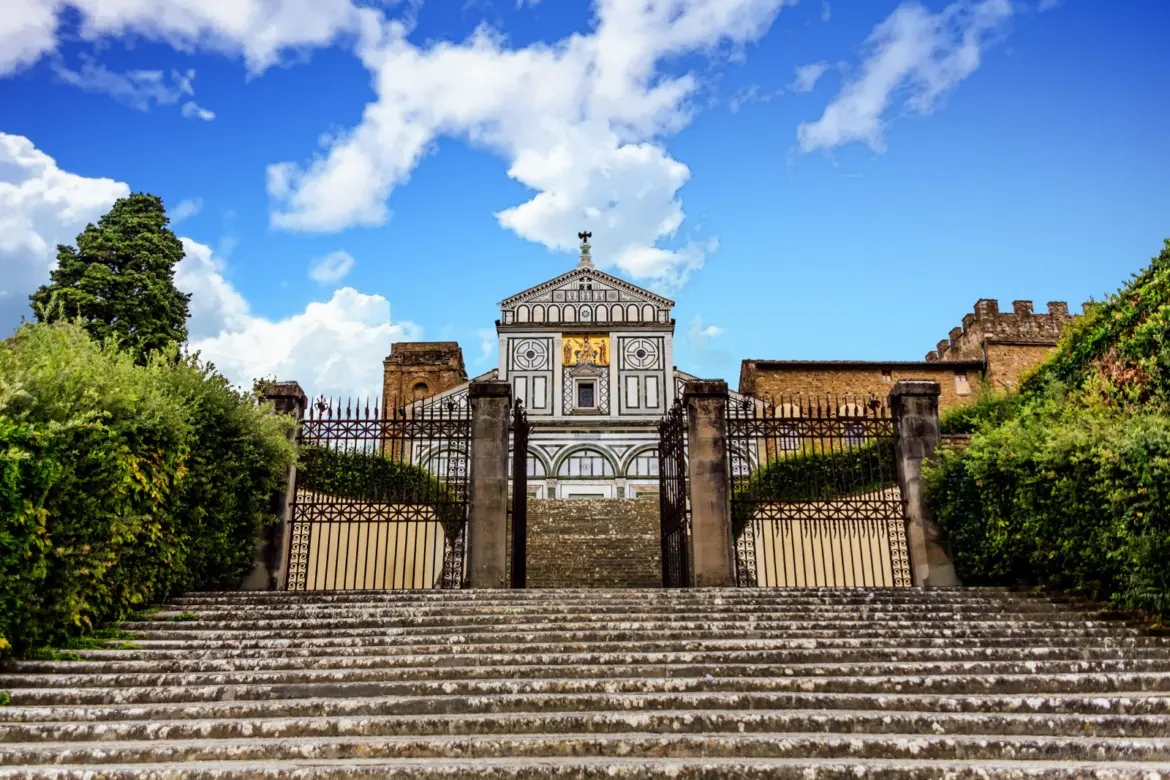 San Miniato Al Monte Staircase Facade Florence Stone staircase leading up to San Miniato al Monte in Florence, with the Romanesque marble façade and golden mosaic visible at the top beneath a bright blue sky