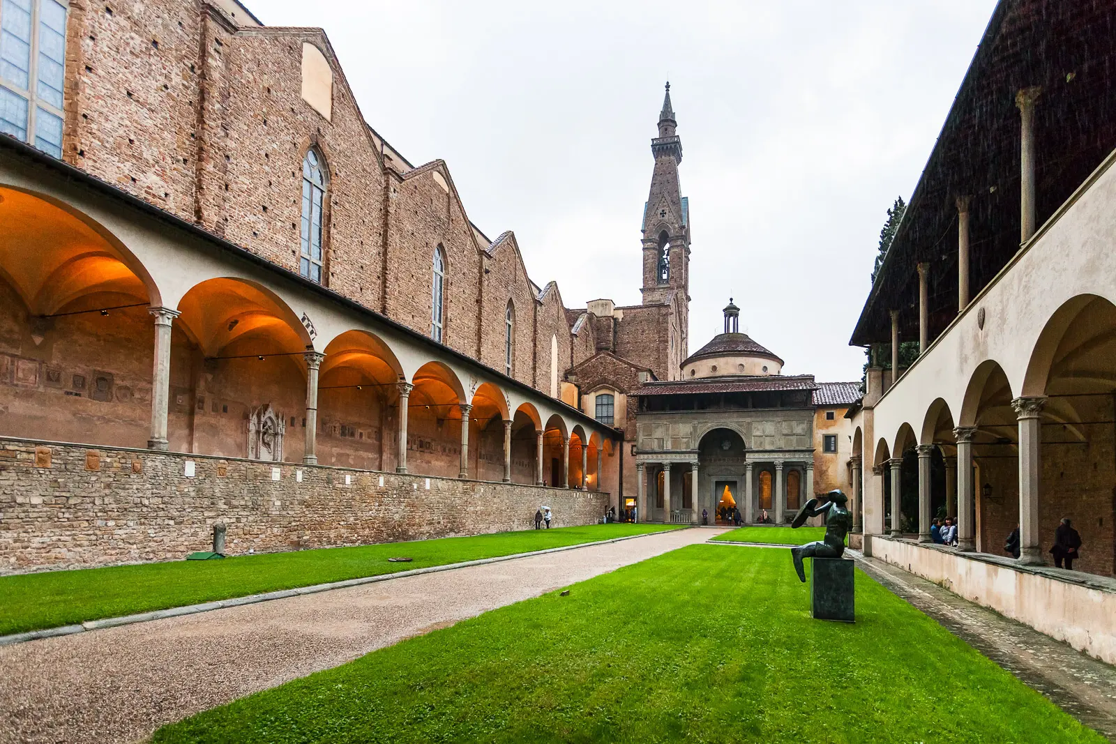 The cloister of Santa Croce Basilica in Florence with Renaissance arcade green lawn and the Pazzi Chapel by Brunelleschi visible in the background