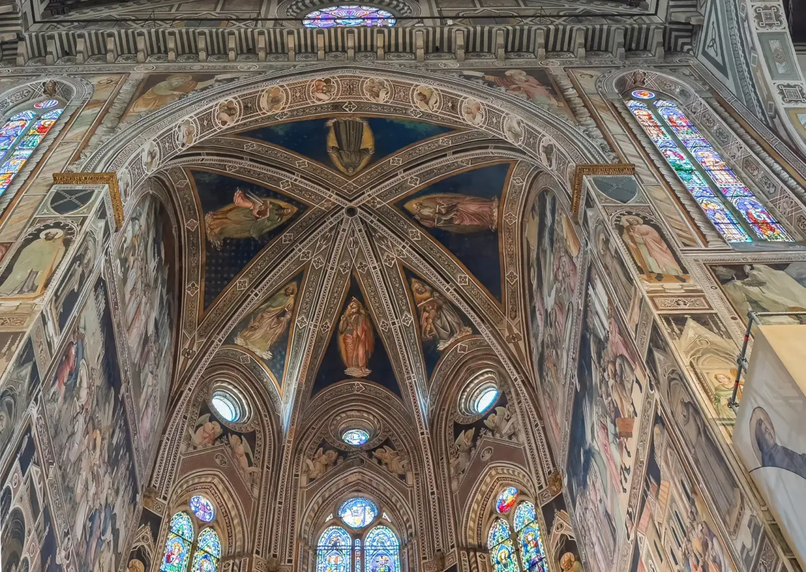 Frescoes and stained glass windows above the high altar of Santa Croce Basilica in Florence showing Gothic ribbed vaulting and early Renaissance painting