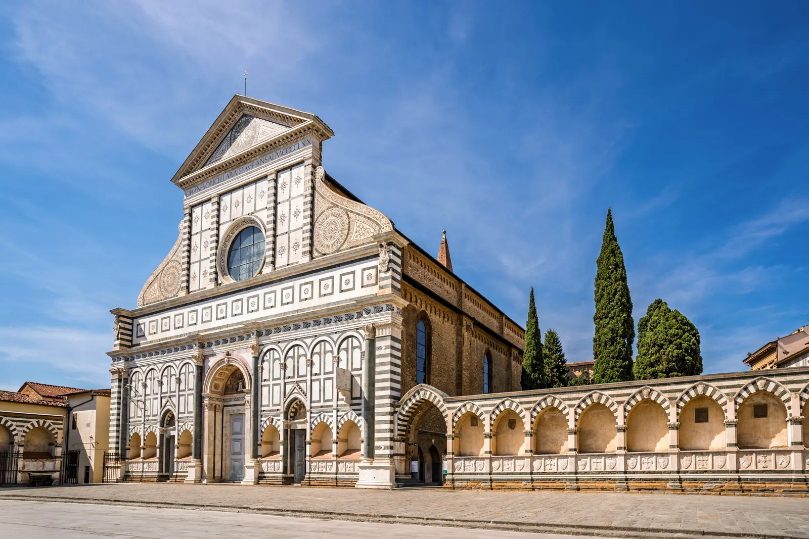 The Renaissance façade of Santa Maria Novella designed by Leon Battista Alberti, showing the green and white marble geometric patterns, scroll volutes, and classical proportions in Florence, Italy