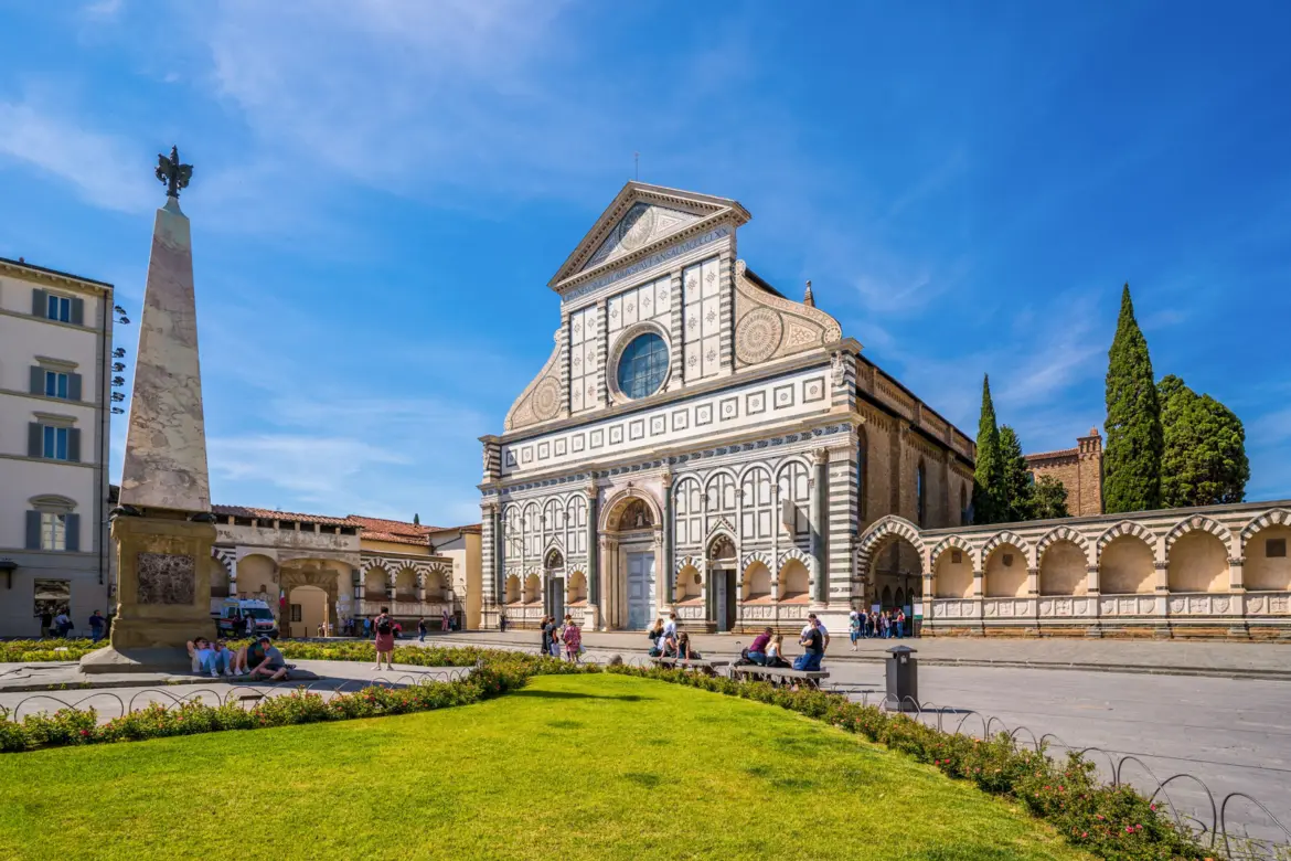Santa Maria Novella Facade Piazza Obelisk Florence Santa Maria Novella church viewed from Piazza Santa Maria Novella in Florence, Italy, with the green and white marble Renaissance façade, marble obelisk, and visitors on the lawn