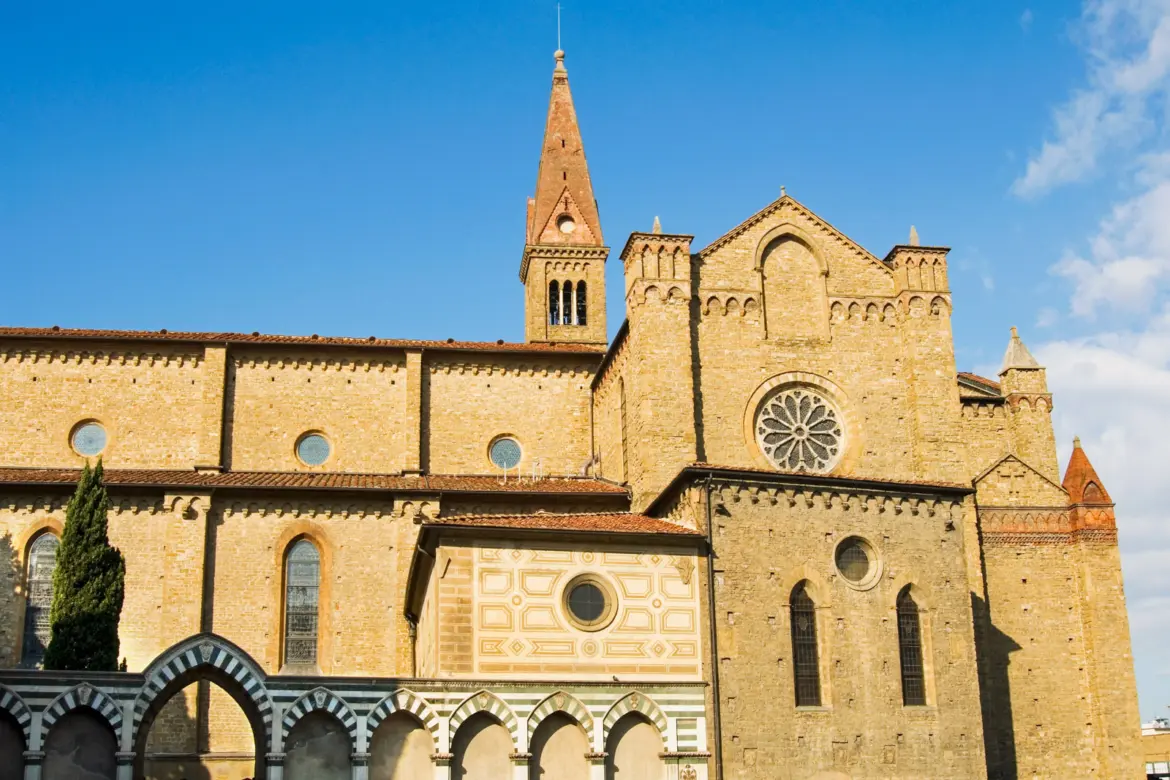 Side view of Santa Maria Novella in Florence revealing the original Gothic stone structure, bell tower, and rose window that contrast with Alberti’s Renaissance façade