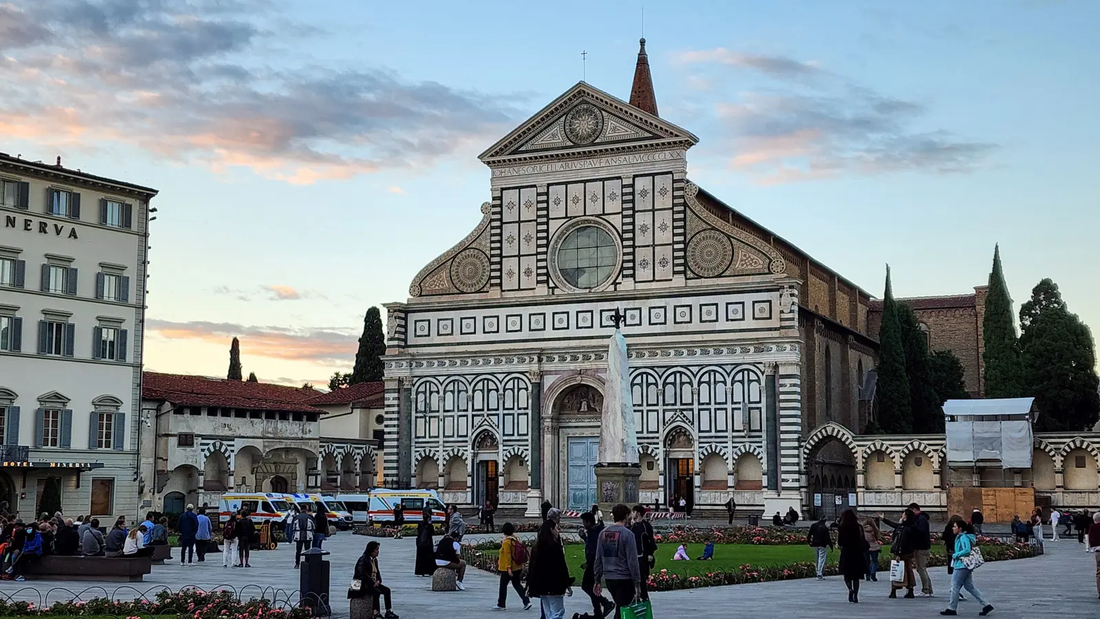 Santa Maria Novella church at sunset seen from Piazza Santa Maria Novella in Florence, with visitors and locals walking through the square in the warm evening light