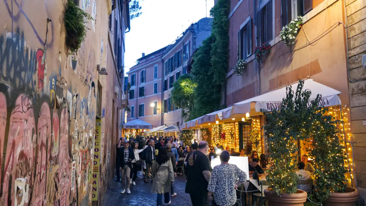 Trastevere neighborhood in Rome Italy at night with cobblestone streets glowing lanterns ivy-covered buildings and lively restaurants