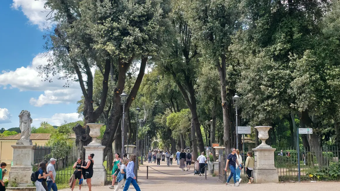 Villa Borghese gardens in Rome with a tree-lined path green lawns and soft dappled light