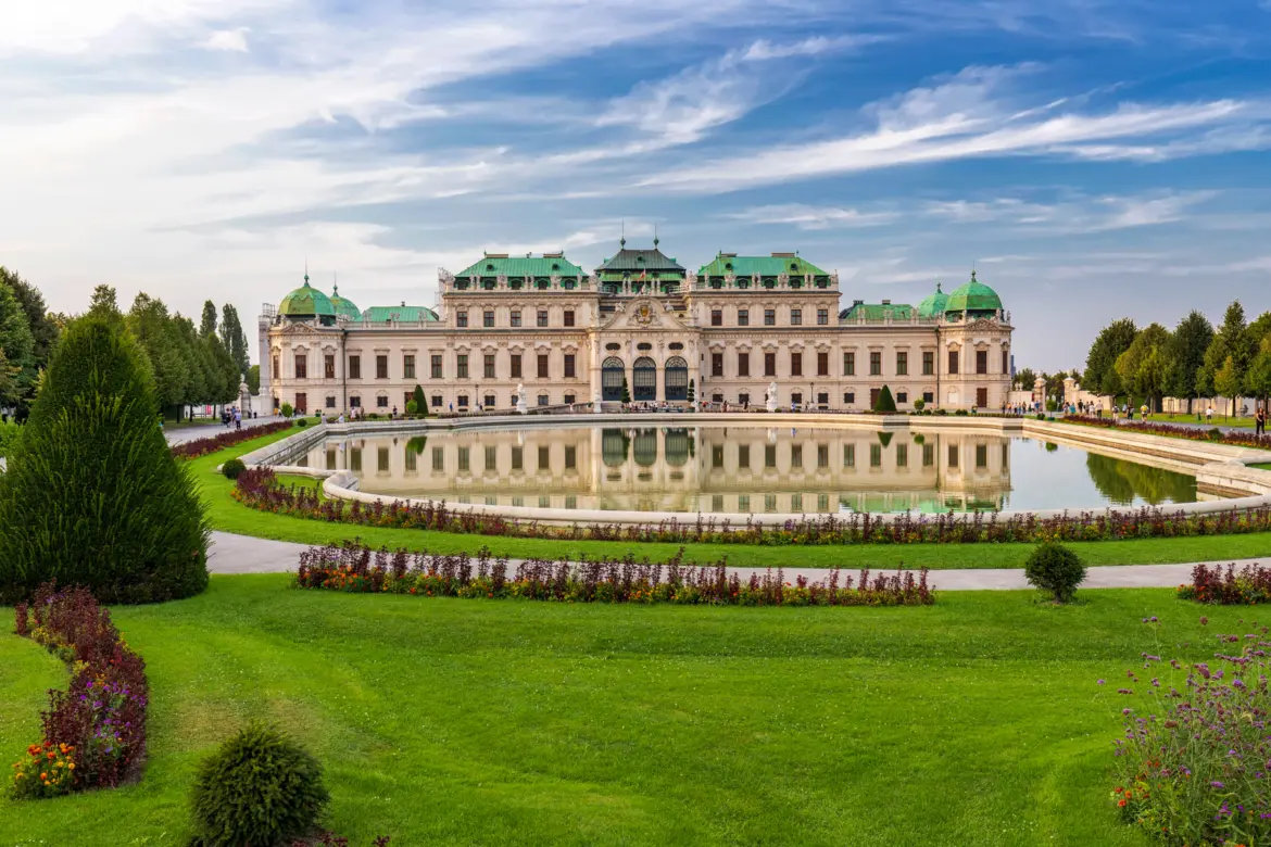 The Upper Belvedere Palace in Vienna reflected in the large pool surrounded by formal Baroque gardens