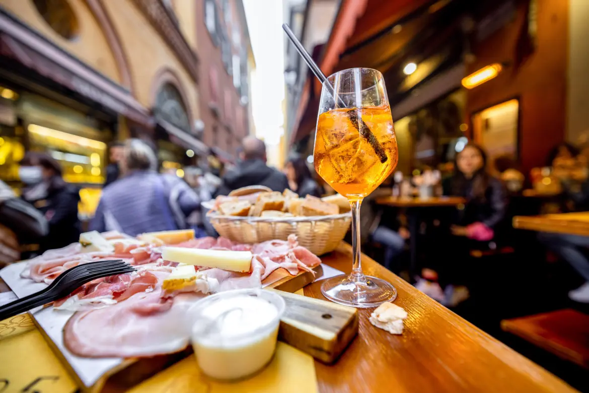 Traditional Italian charcuterie platter with local cheeses and Aperol Spritz, capturing Bologna’s famous aperitivo culture