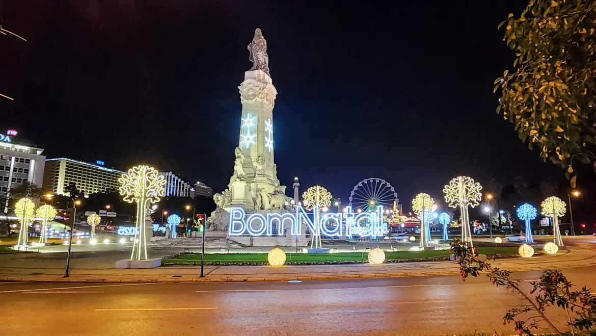 Marquês de Pombal roundabout with Bom Natal lights illuminated trees and Wonderland Lisboa Ferris wheel in the background in Lisbon at night