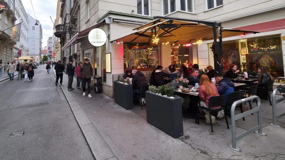 Outdoor patio dining at Chinacy restaurant in Vienna on a cozy autumn evening, with warm lighting and street-level atmosphere