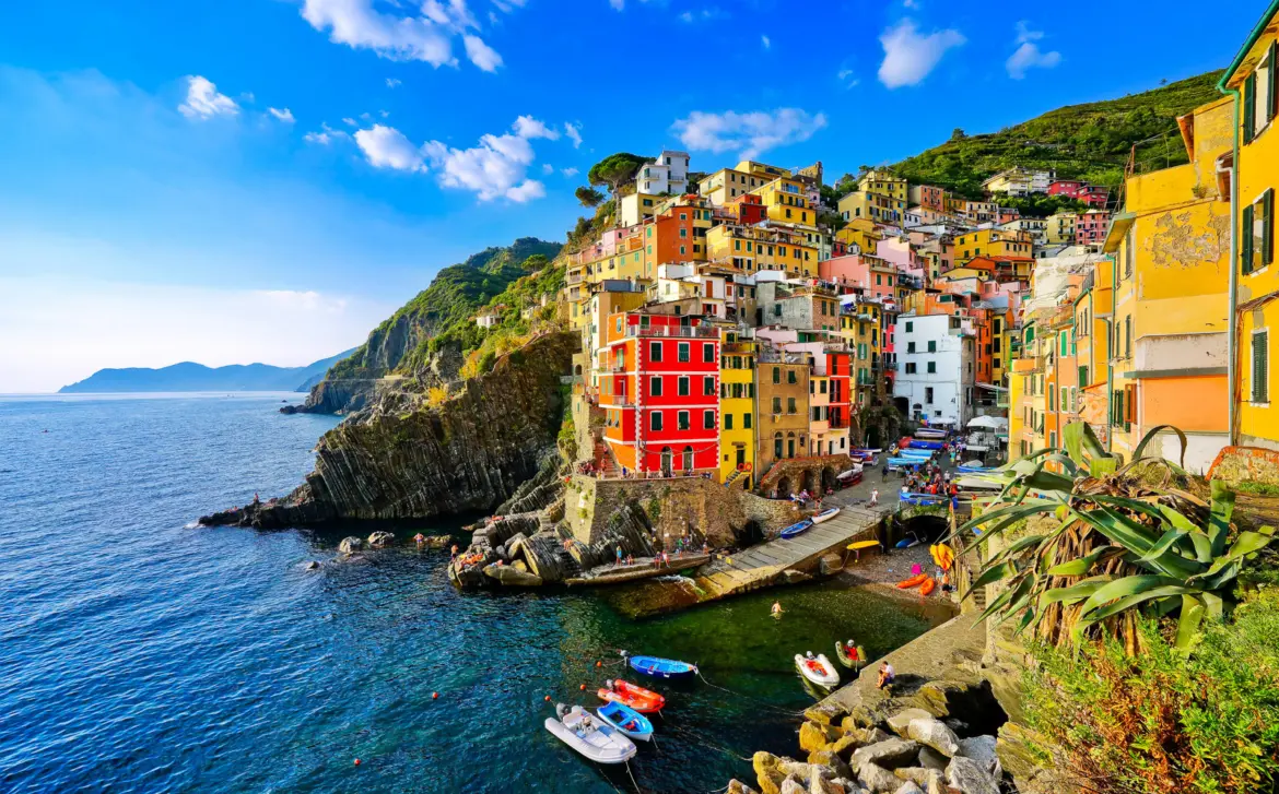 Colorful houses cascading down the cliffs of Riomaggiore in Cinque Terre, where pastel buildings meet the Ligurian Sea